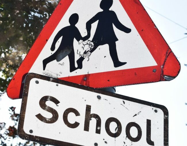a red and white sign that says school and a black and white sign that says